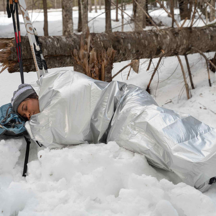 Compact survival bivvy with rescue whistle and fire-starting tinder cord