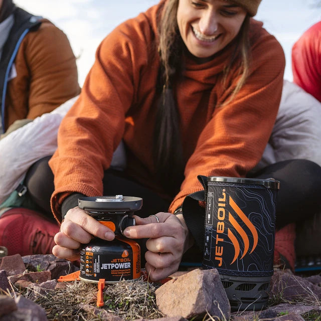 The Jetboil Flash Java 1.0L displayed with compatible accessories like the Hanging Kit 2.0, Pot Support 2.0, Summit Skillet, and 1.5L Ceramic Cook Pot, showing its versatility for outdoor cooking.