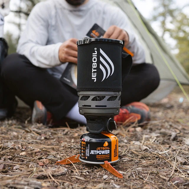 The Jetboil Zip 0.8L alongside compatible accessories like the Hanging Kit 2.0, Pot Support 2.0, Summit Skillet, and 1.5L Ceramic Cook Pot, showing versatility in outdoor cooking.