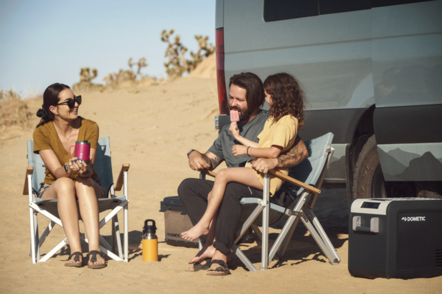 Dometic CMP C1 Compact Camp Chair set up by a campfire, illustrating its outdoor use and comfortable design.