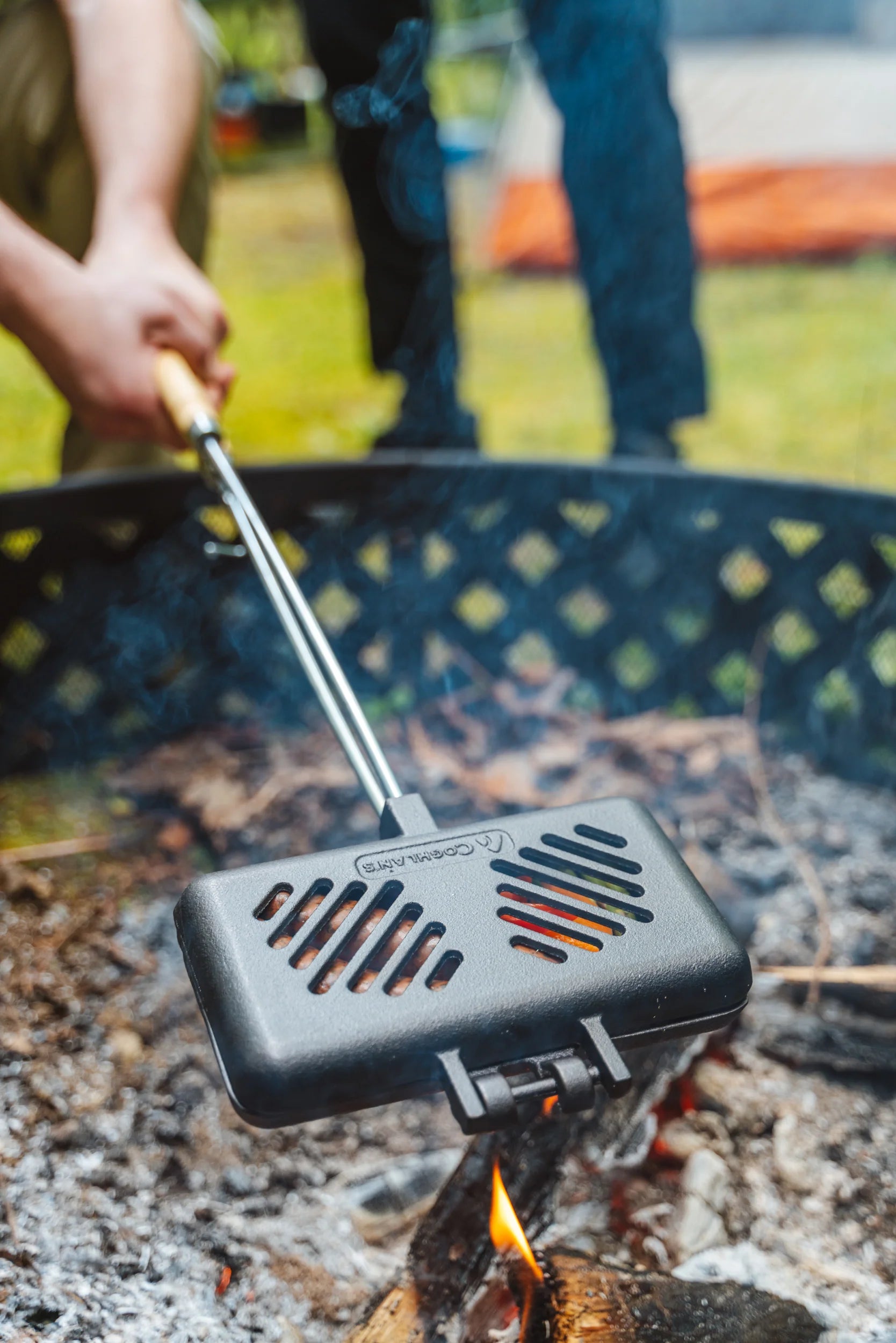 Outdoor cast iron broiler separated into two hinged pieces for easy cleaning, ideal for camping and open-fire cooking