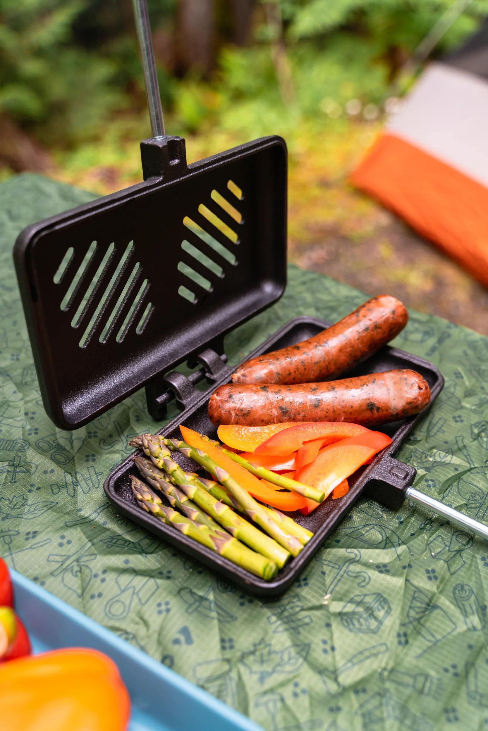 Heavy-duty camping broiler with slotted cast iron plates, perfect for grilling meats and roasting vegetables at the campsite