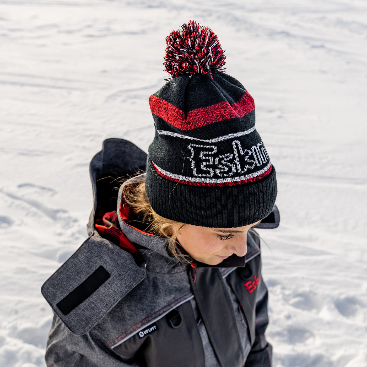 Side view of black fleece-lined pom hat on white background