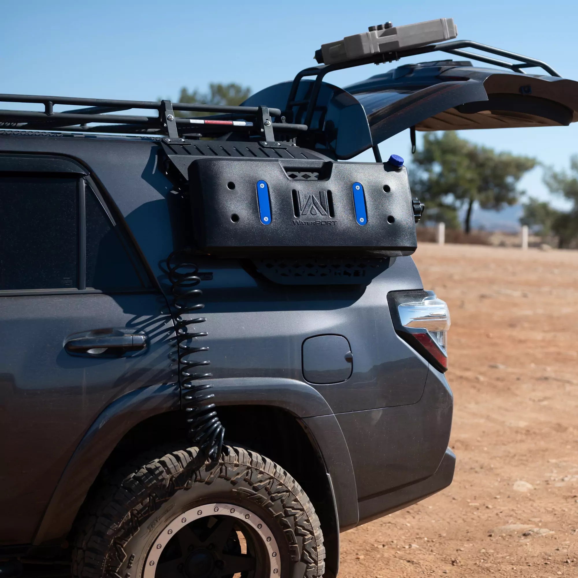 Overlander Tank in Use at a Campsite – A camper using the pressurized spray nozzle to rinse off gear.
