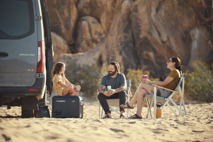 Dometic CMP C1 Compact Camp Chair set up by a campfire, illustrating its outdoor use and comfortable design.