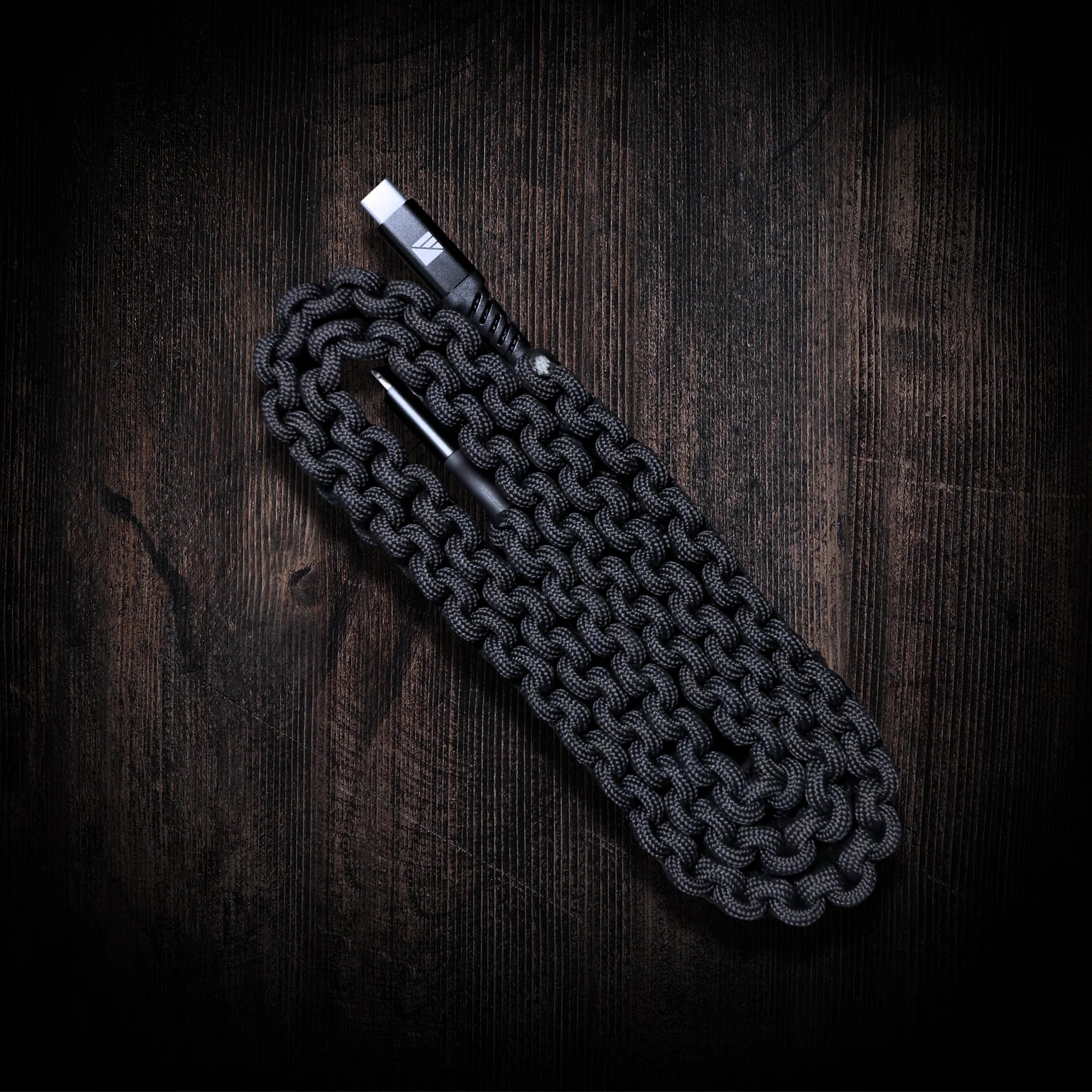 Dark Energy USB-C to USB-C Cable featuring durable paracord wrapping in black, green, and hi-vis colors, shown coiled with a leather strap for cable management