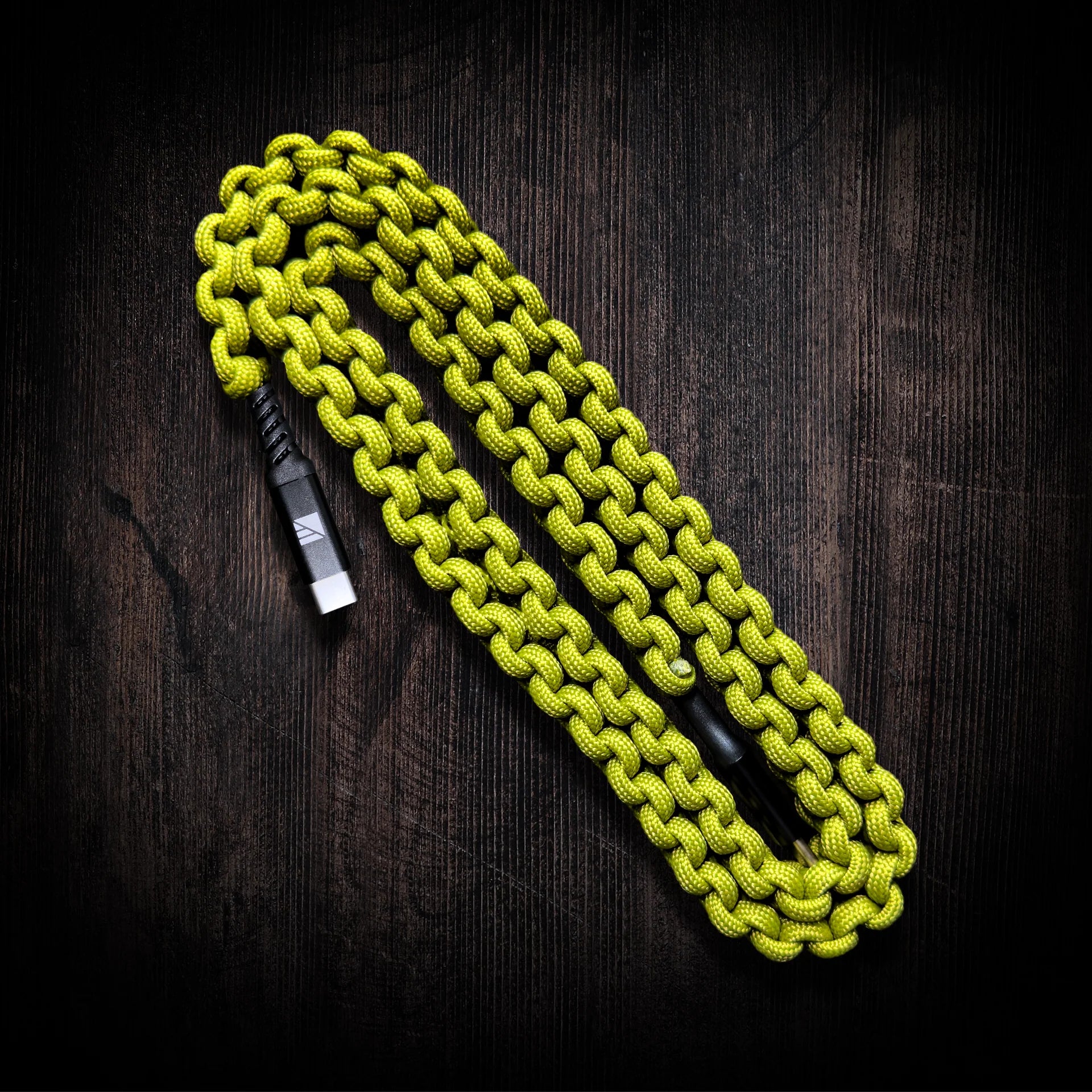 Detailed view of the 550 lb certified paracord wrapping, showcasing its rugged texture and available color options: black, hi-vis, and green.