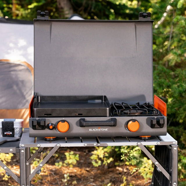 Side view of the Blackstone camping griddle showing the lit side burner in use, ideal for heating water or cooking soup alongside griddle-cooked meals