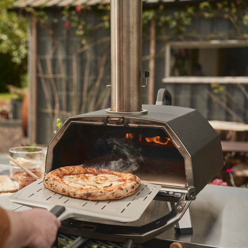 Self-cleaning pizza oven stone with removable fuel tray for easy ash disposal