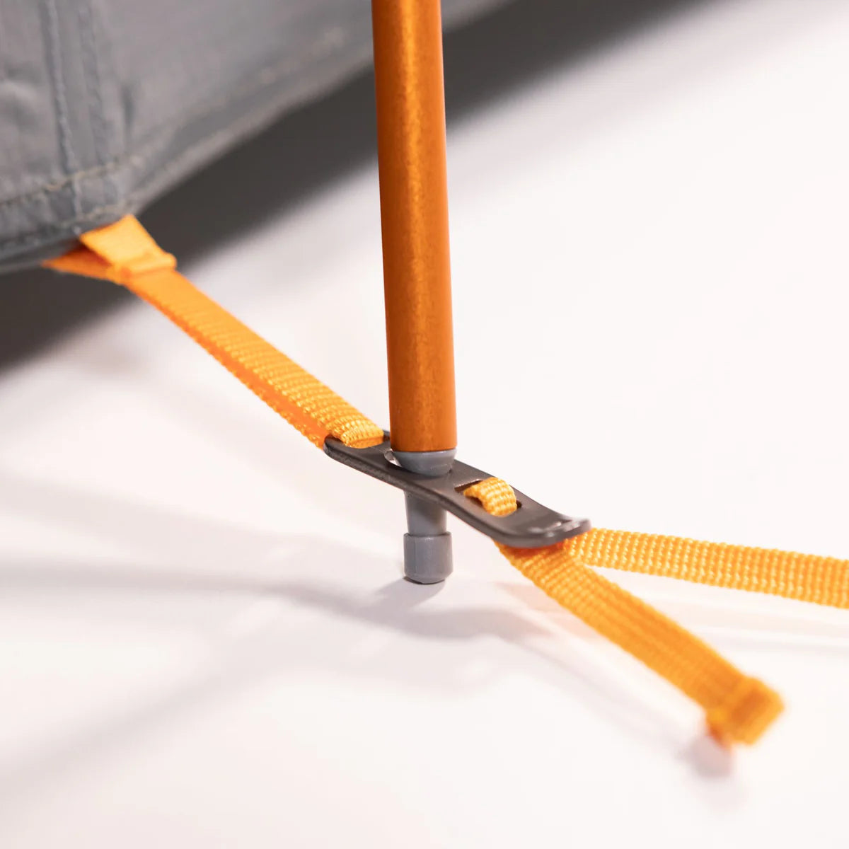 Close-up of a camping tent pole with orange straps on a white background