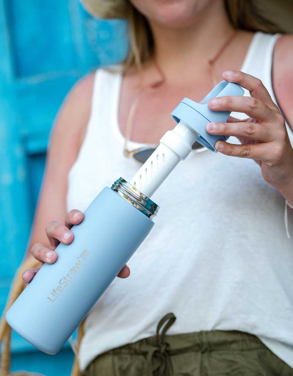 Close-up of the LifeStraw membrane microfilter and activated carbon filter components. Text explains their removal capabilities, including 99.999999% of bacteria, 99.999% of parasites, and microplastics, as well as chlorine and odors.