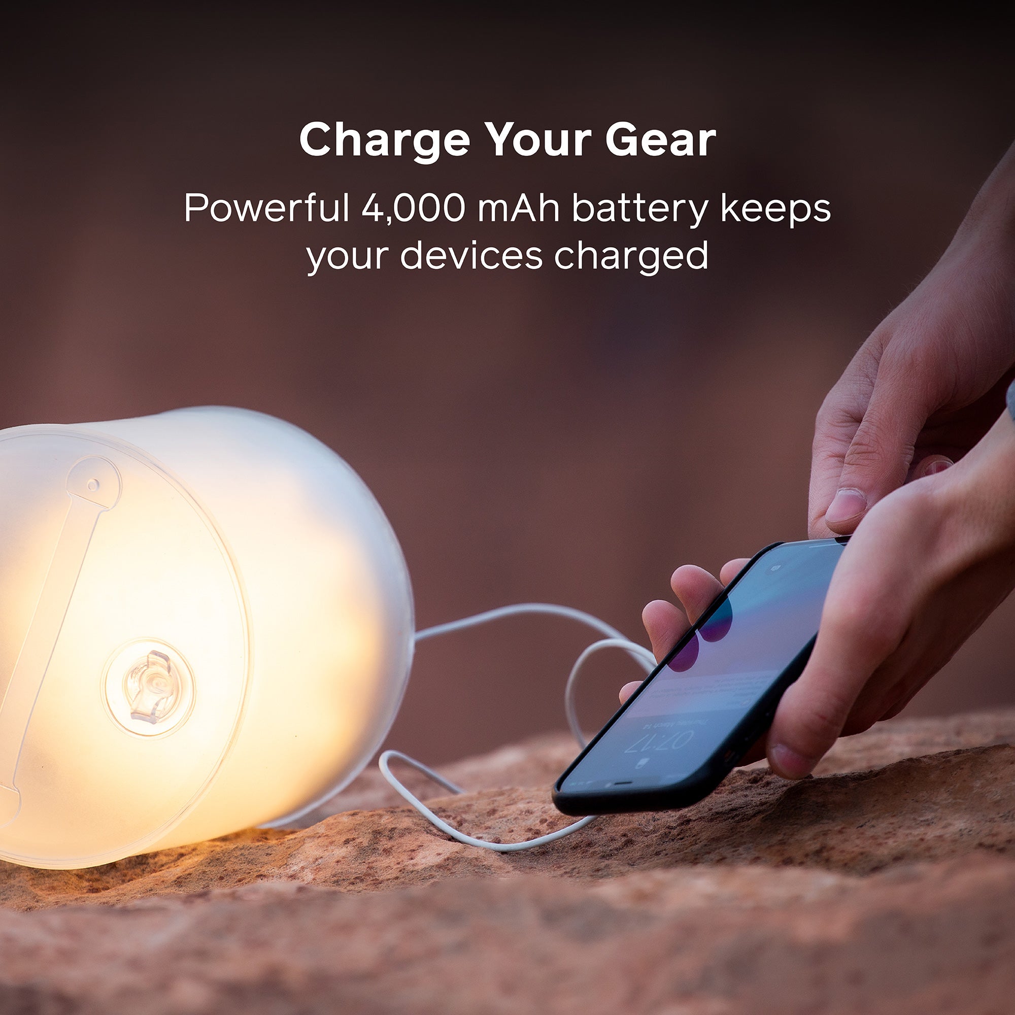 Person charging a smartphone with a portable light device, emphasizing a 4,000 mAh battery capacity.