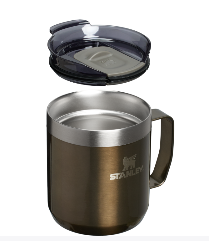 Man sipping coffee from Stanley mug by the campfire