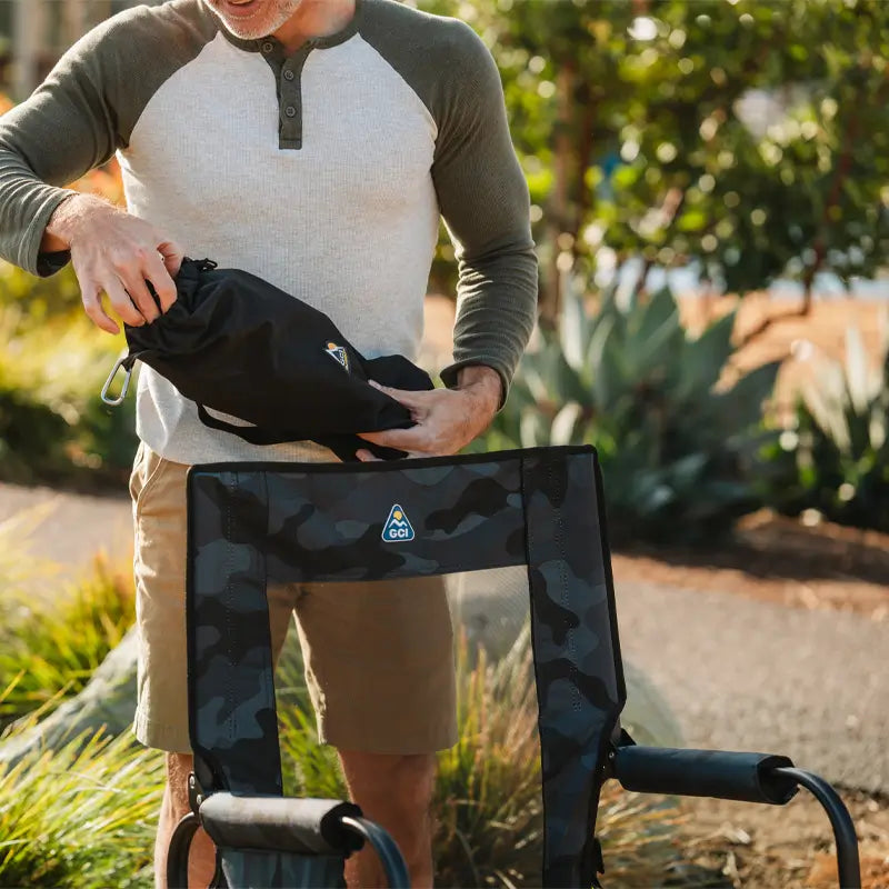 Person holding a black bag with a camouflage design outdoors