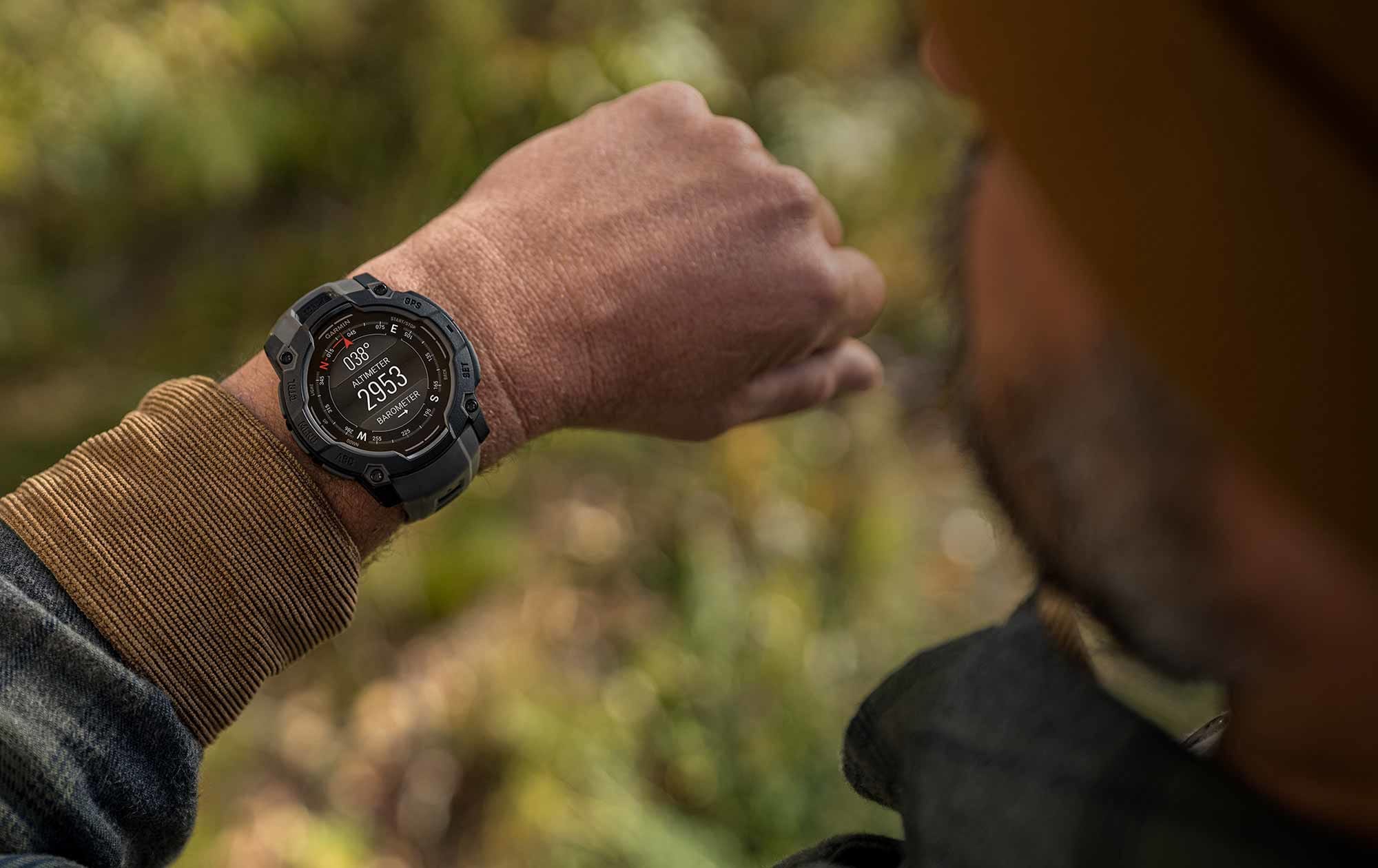 Person wearing a rugged watch outdoors with a blurred natural background