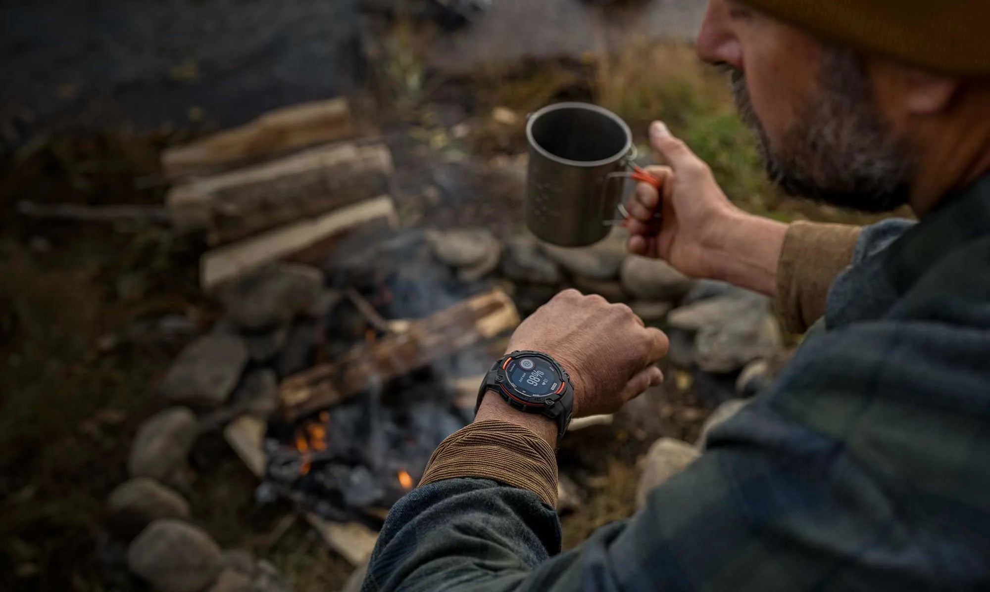 Person holding a mug by a campfire in a natural setting