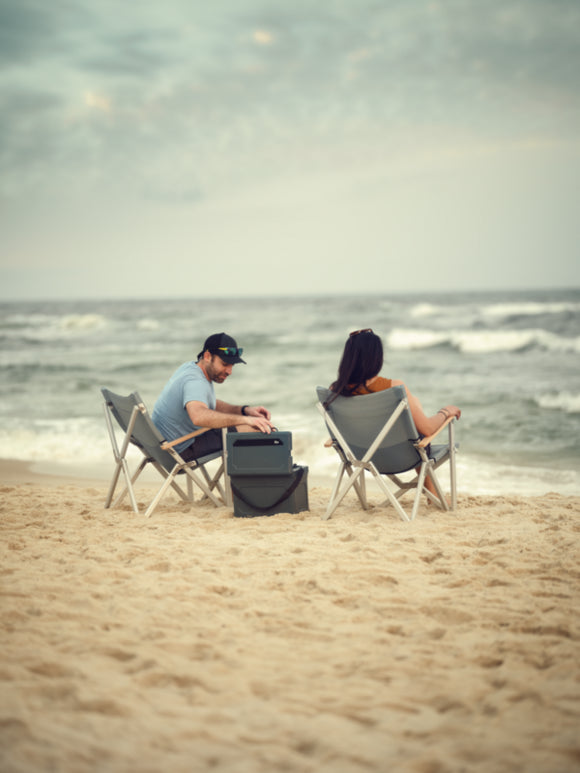 Dometic CMP C1 Compact Camp Chair set up by a campfire, illustrating its outdoor use and comfortable design.