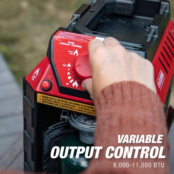 Person adjusting a variable output control on a portable heater with visible text.