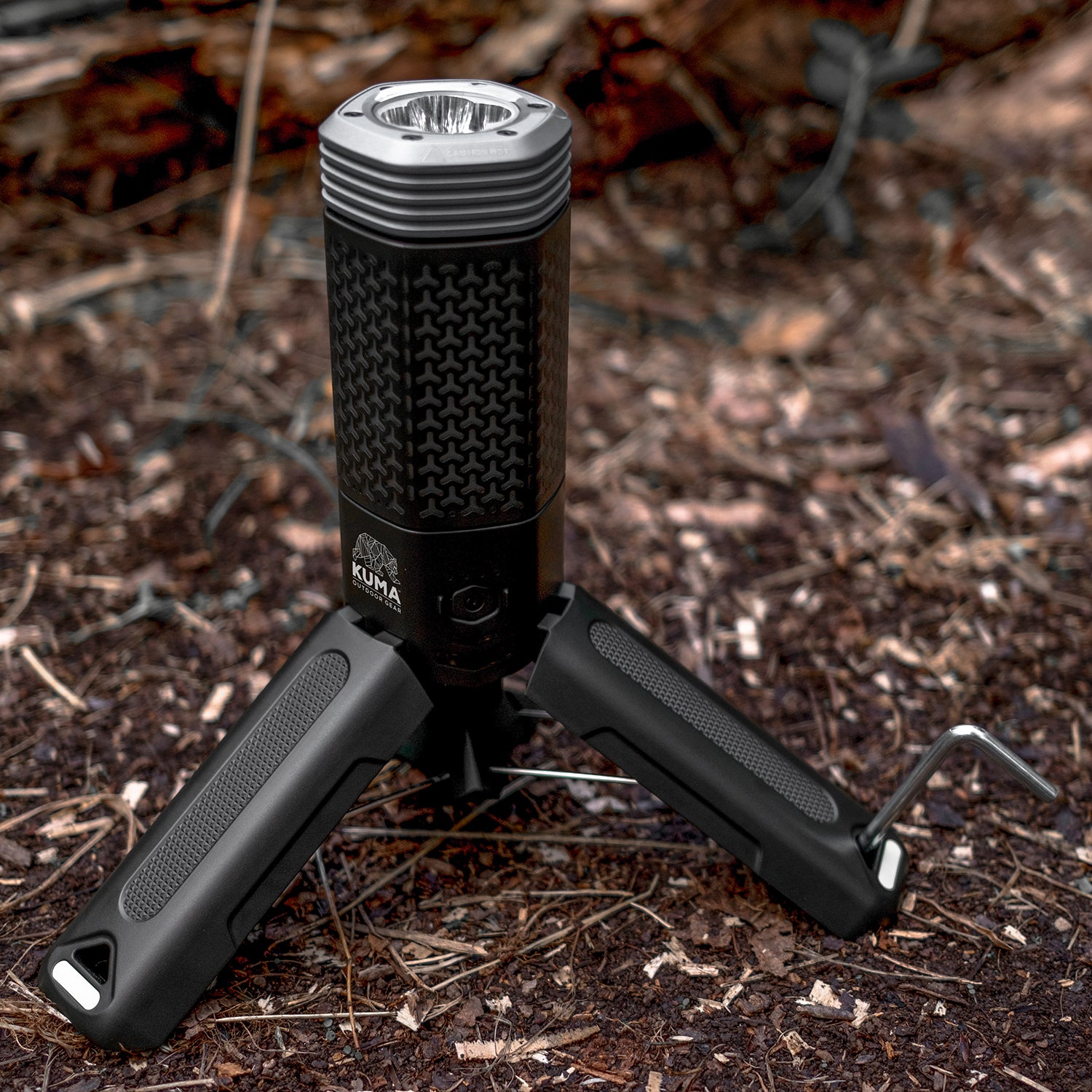 Black flashlight with tripod stand on a forest floor