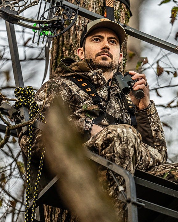 Hunter using Triumph HD 10x28 binoculars for spotting wildlife in the field