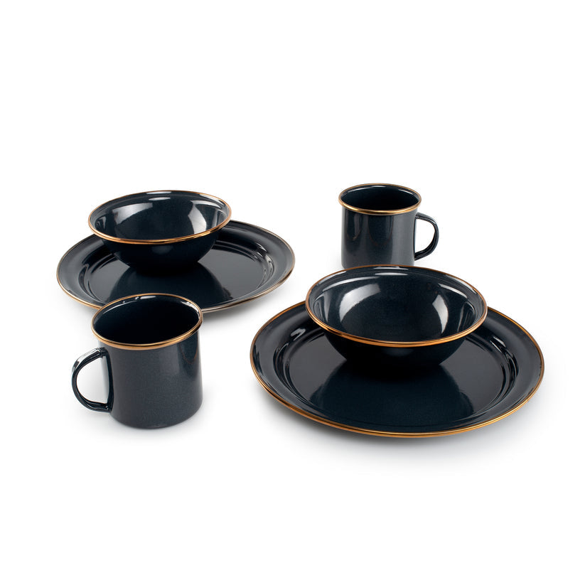 Set of black ceramic dinnerware with gold rims on a white background