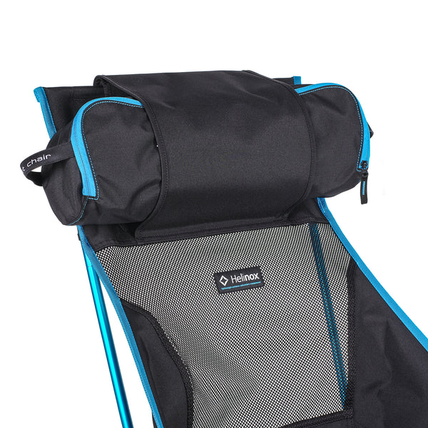 Helinox Sunset Chair set up at a campsite, showcasing its supportive high back and convenient headrest flap for extra comfort during outdoor adventures.