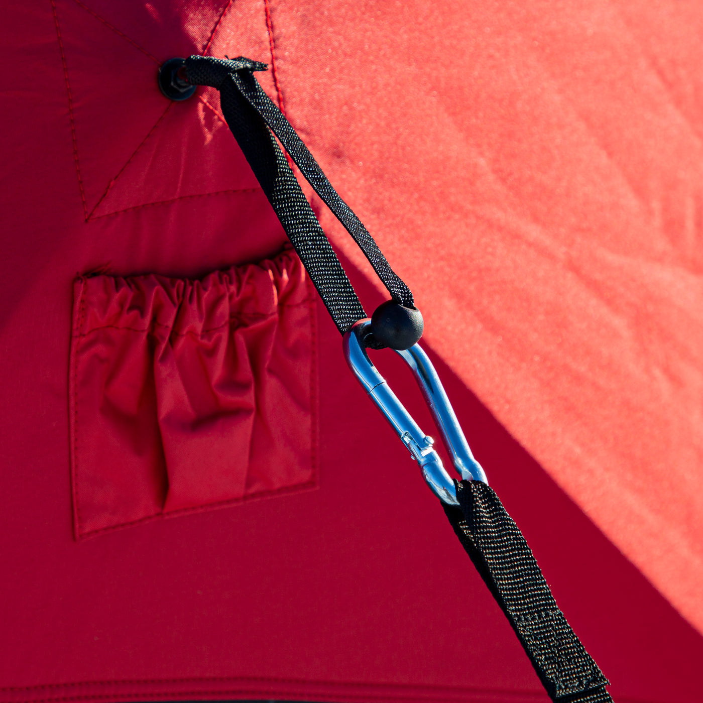 Detailed view of a self-tapping ice anchor with a sharp point being screwed into ice by hand.

