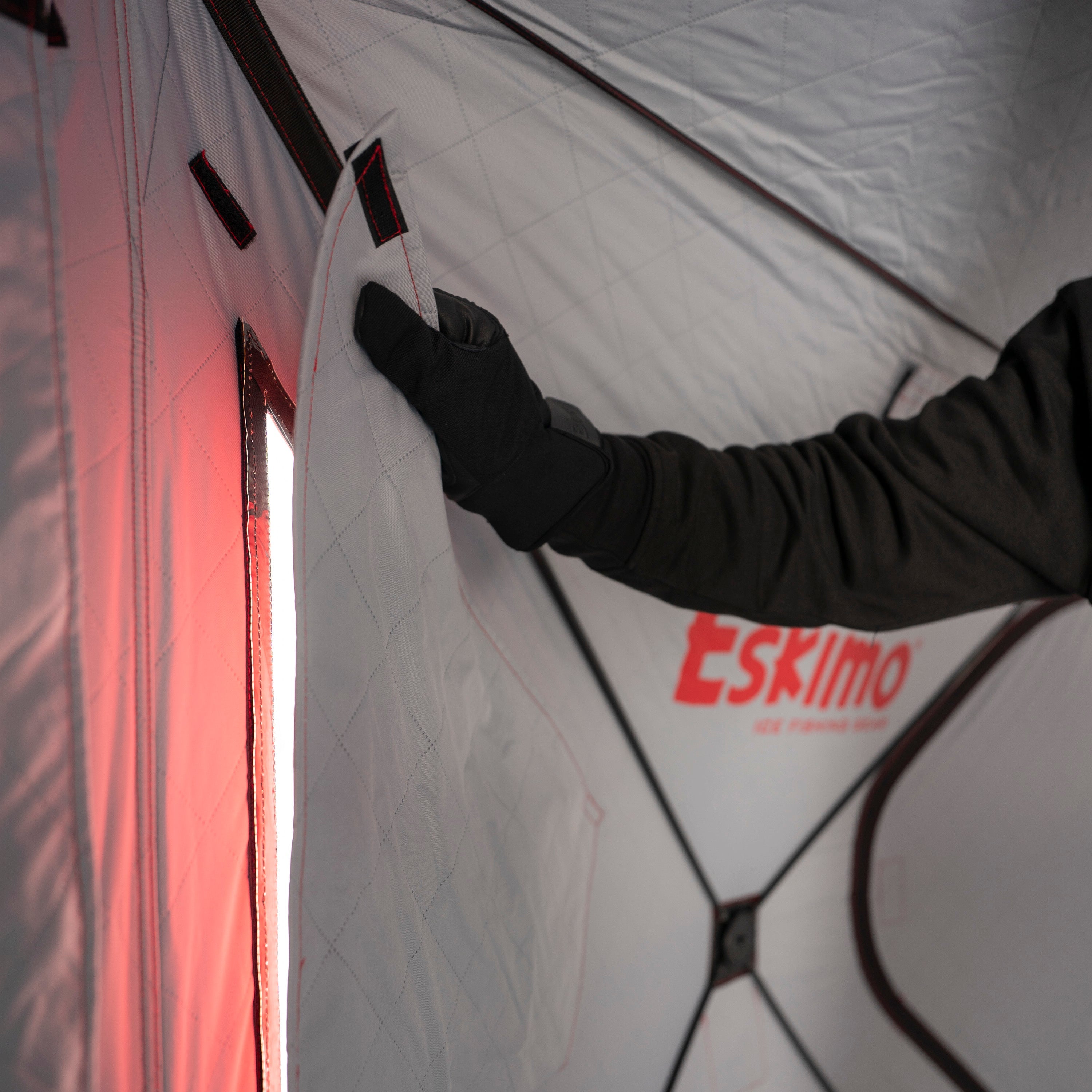 Person adjusting a tent with 'Eskimo' branding inside