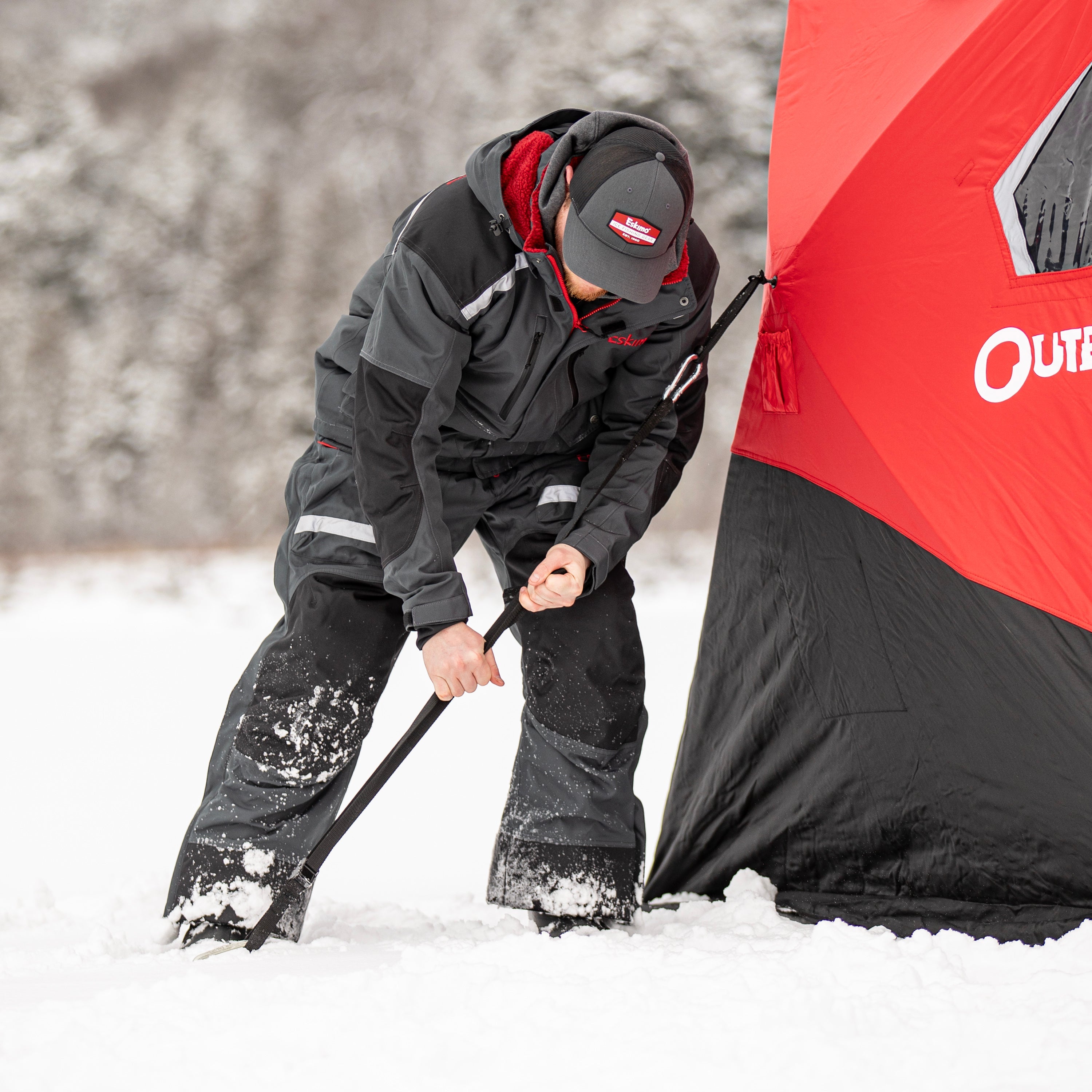 Person setting up a tent in the snow with a visible brand logo.
