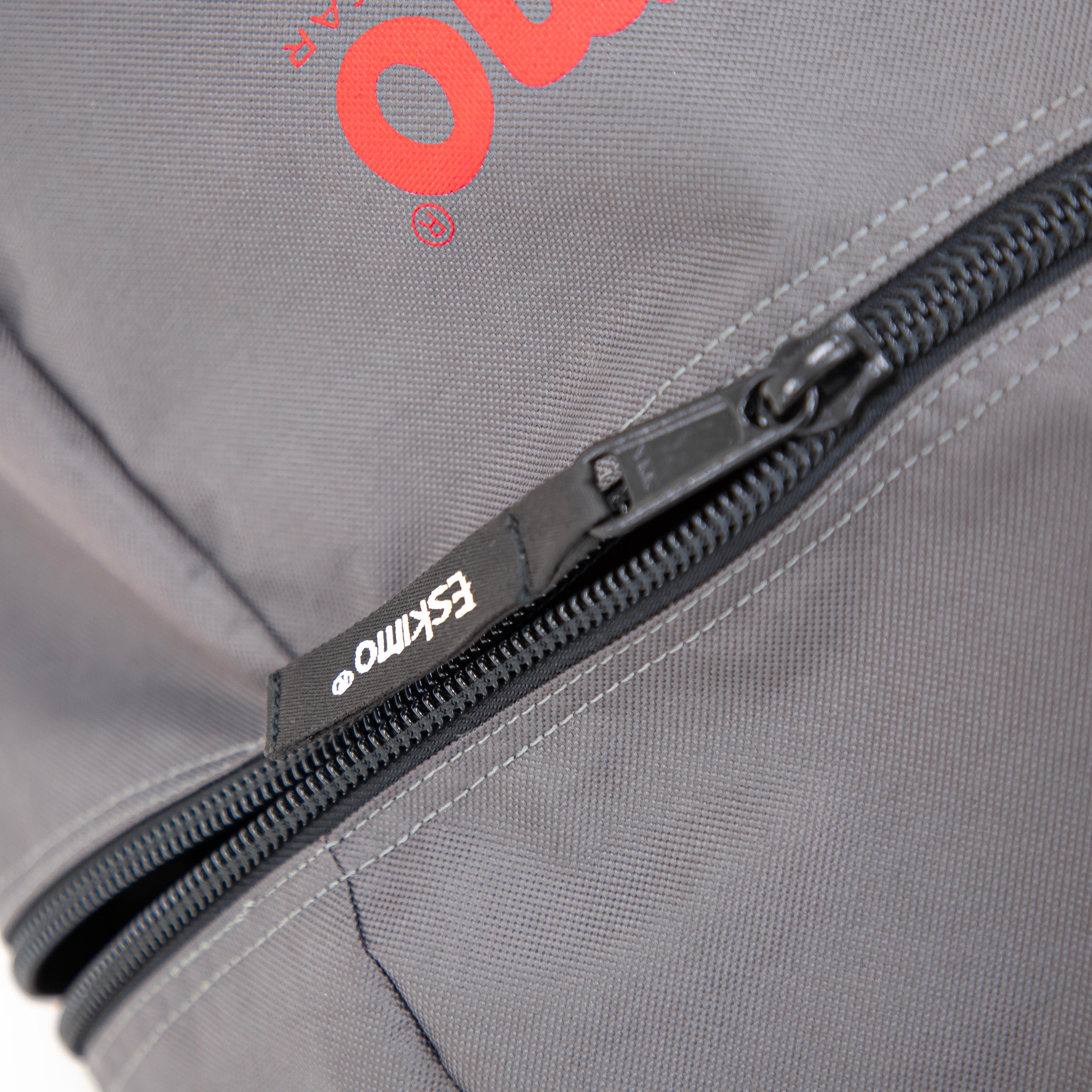 Close-up of a gray bag with a black zipper and red logo, featuring the brand 'Eska'.