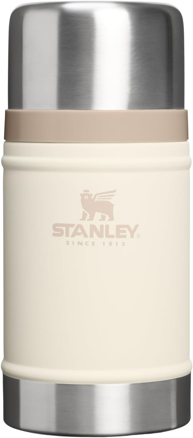 A Stanley vacuum-insulated water bottle with a cream-colored body, a beige band, and a brushed stainless steel lid and base, featuring the Stanley logo on the front.