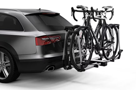 Car with a bike rack attached to the back, holding two bicycles.