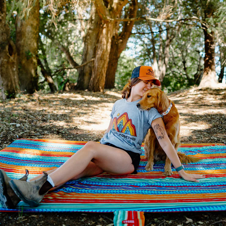 Outdoor blanket anchored on grassy terrain during a music festival