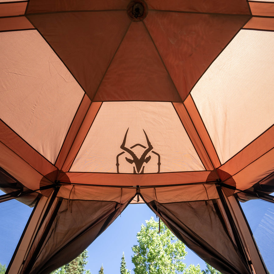 Gazelle G6 Cool Top 6-sided gazebo with open mesh windows in a forest clearing during summer camping trip