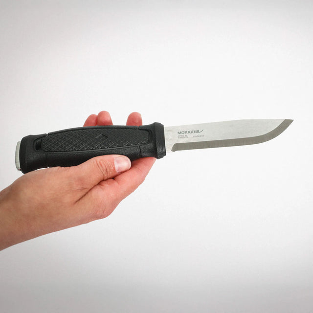 Hand holding a knife with a black handle and silver blade on a white background