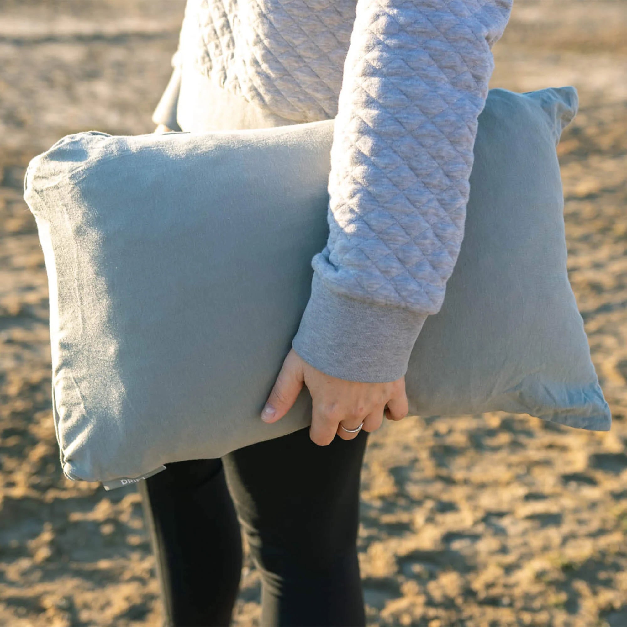 A person holding the Drift Pillow in its packed form, demonstrating its lightweight and portable size for easy carrying on the go.