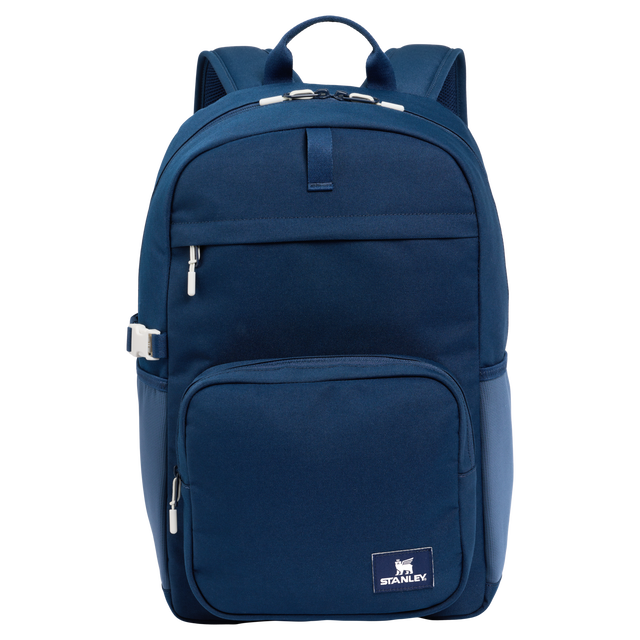 Front view of the Assembly Backpack in a sleek design, showing adjustable padded straps, front zippered pockets, and side pockets designed for a Stanley bottle.