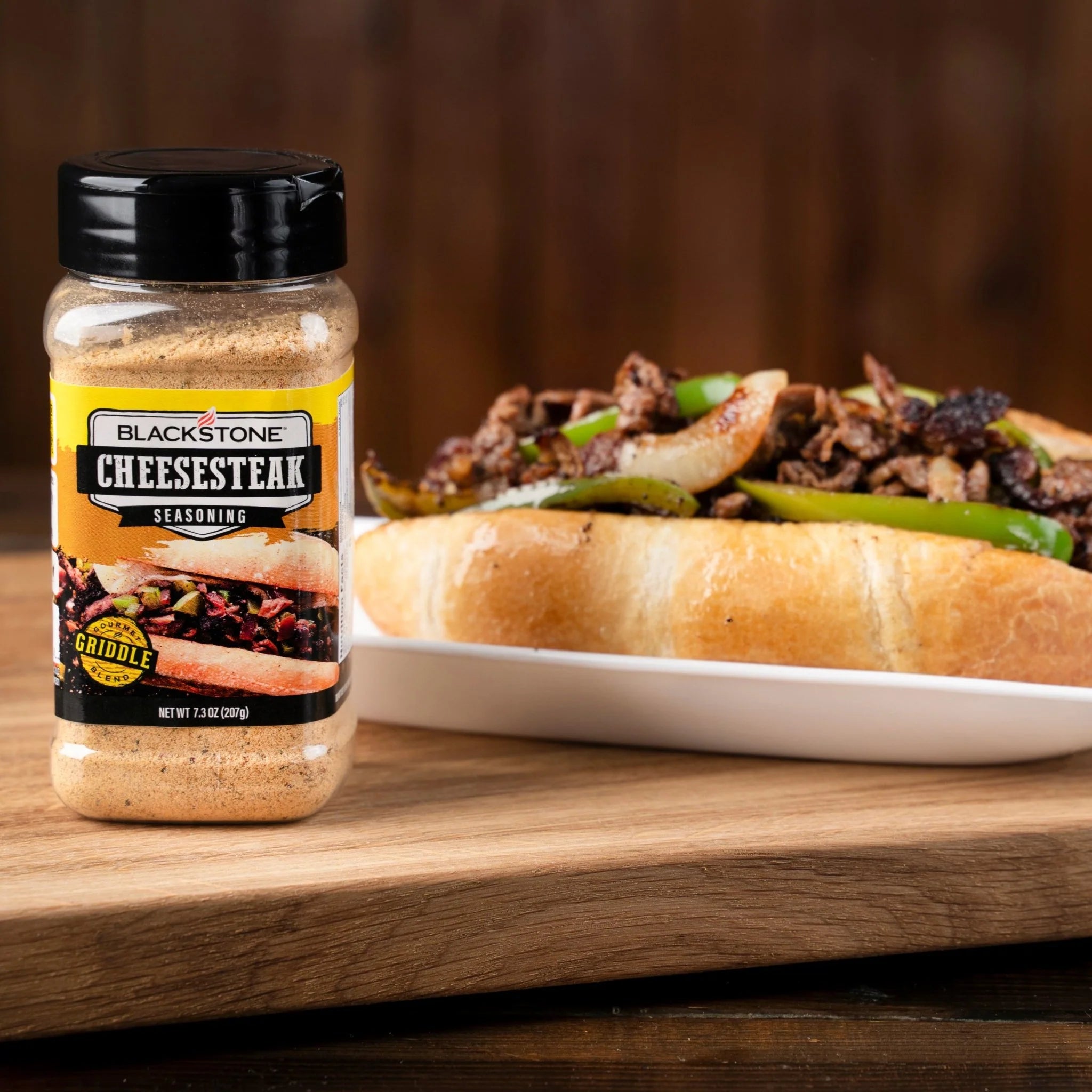 Sprinkling Blackstone Cheesesteak Seasoning on sizzling steak slices

