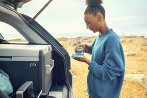 The Dometic CFX3 55IM cooler in use during an outdoor adventure. The cooler is powered by solar energy and is keeping food and drinks fresh in a remote location, demonstrating its versatility and efficiency