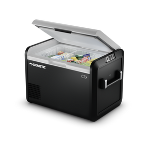 The Dometic CFX3 55IM, a tall portable electric cooler, featuring a sleek design with lightweight fender frames, strong aluminum alloy handles, and a high-resolution color display. The cooler is shown on a rugged outdoor background, highlighting its durability and portability