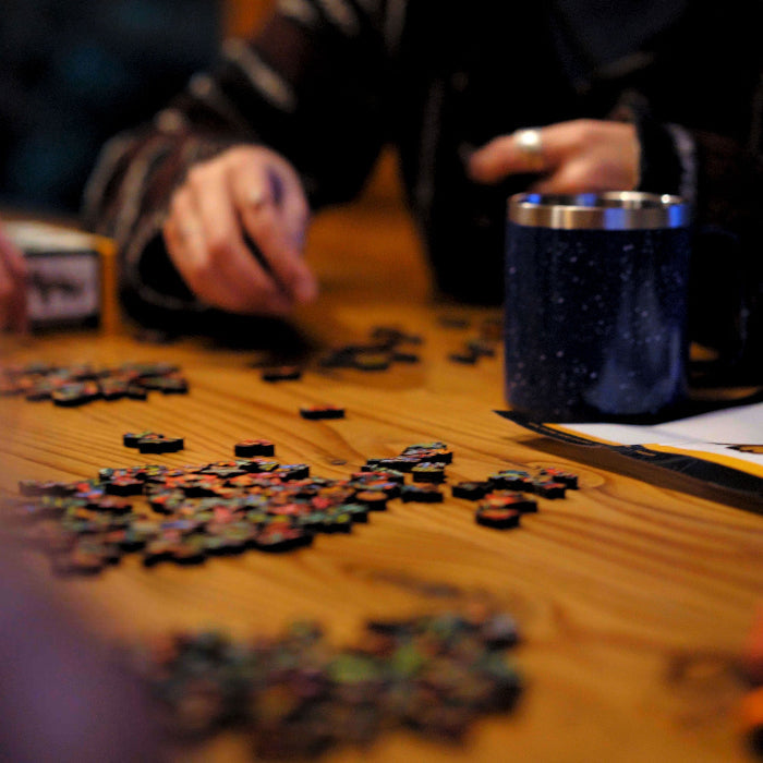 Person playing a board game with pieces and a mug on a wooden table