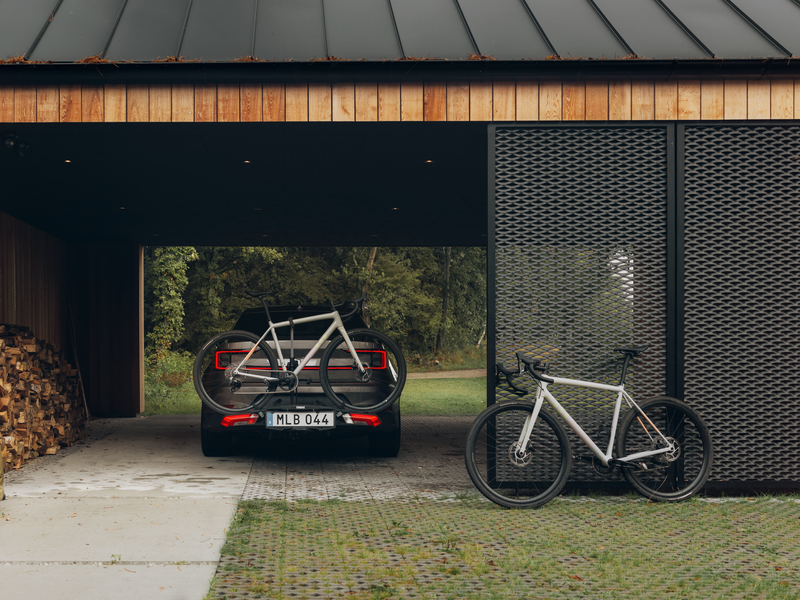 Thule Epos bike rack with bikes mounted, allowing easy access to the car trunk using the smart foot pedal tilt feature